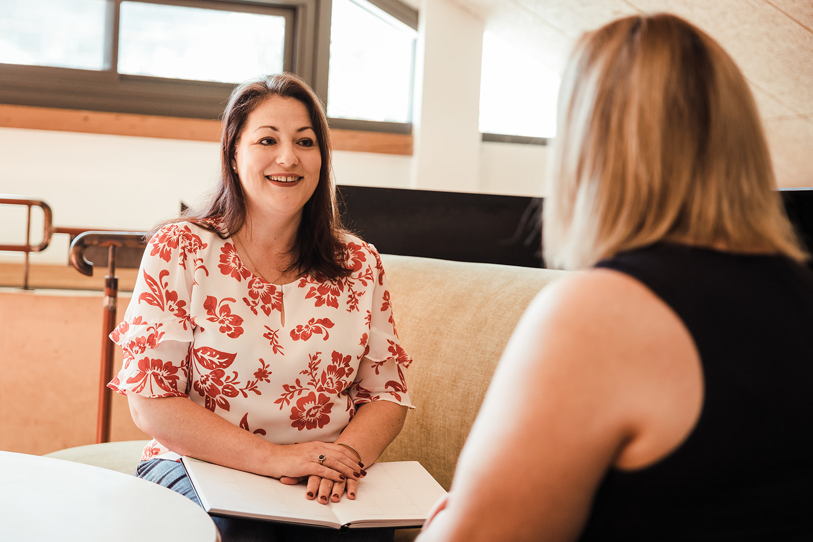 Alanna in a white top with red flowers speaking to a client.